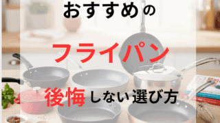 明るいキッチンカウンターの上に、様々な素材とサイズのフライパン、小さな鍋、木べら、泡立て器、料理本などがきれいに並べられている様子。