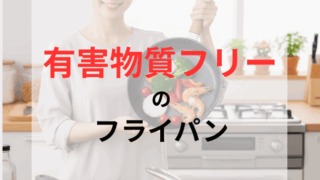 笑顔の日本人女性が、炒め物が盛り付けられたフライパンを両手で持ち上げている。健康的な食材と安全なフライパンでの調理を表現したクローズアップ。