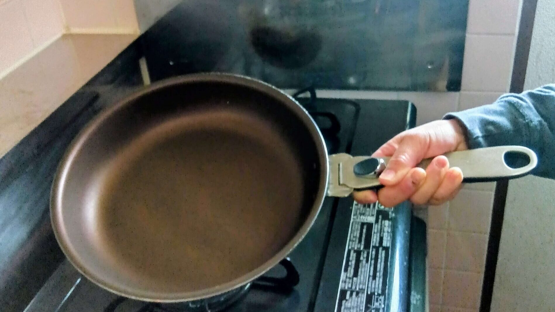 ペンタのフライパンを片手で持ち上げて重さやサイズ感を確認している手元の様子